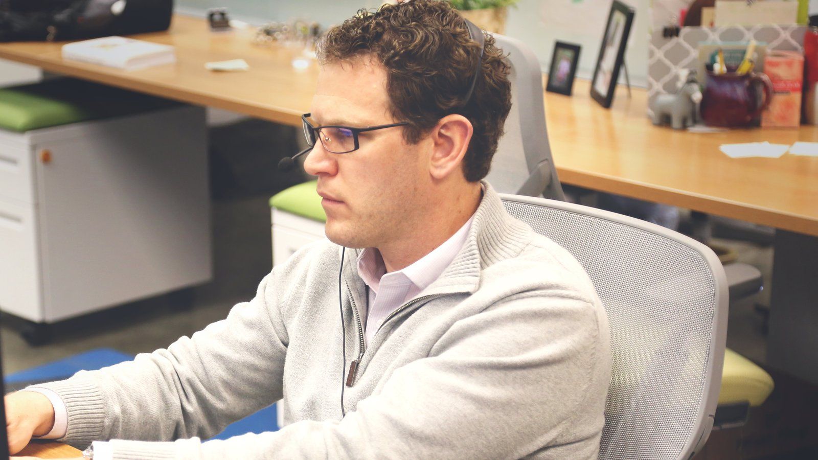 Developer wearing a headset working at a desk in an open plan office