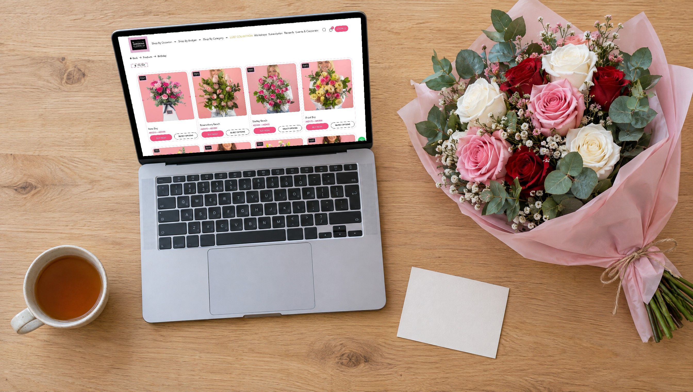 The Gorgeous Flower Co birthday collection on a laptop beside a bouquet of roses